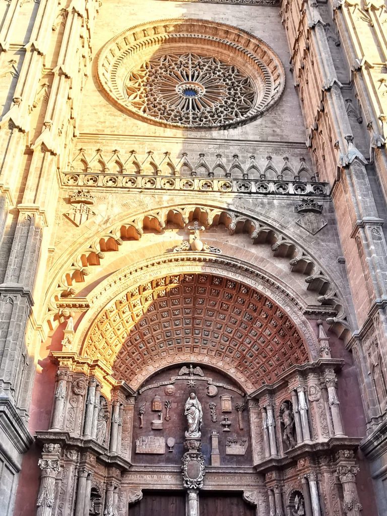 Fassade der Kathedrale La Seu in Palma de Mallorca mit gotischem Rundfenster bei Abendlicht