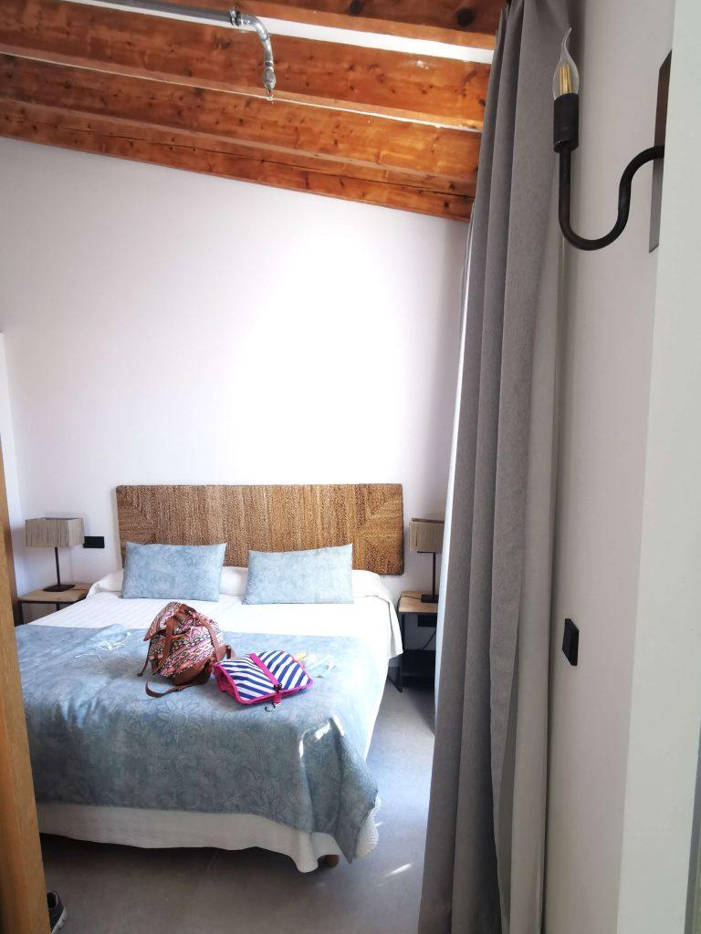 Gemütliches Hotelbett mit rustikalem Holzbalken an der Decke im Ca'n Alexandre