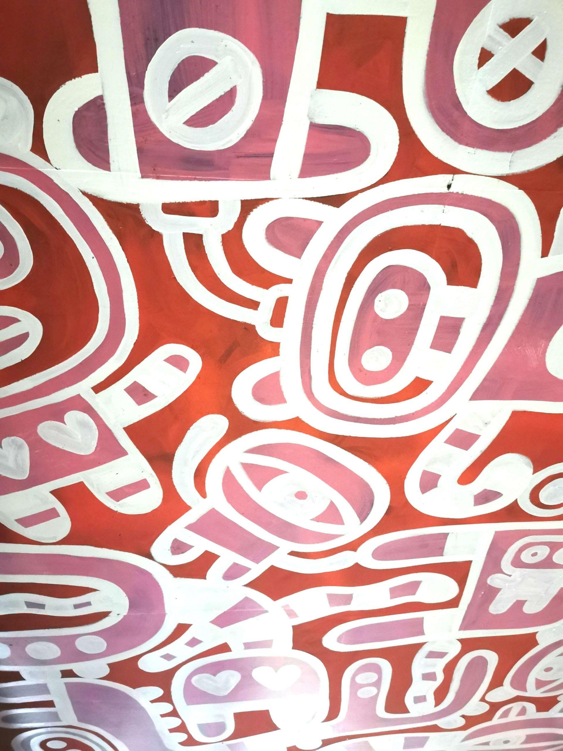 Streetart-Muster in Rosa und Weiß auf rotem Hintergrund in Londons Banksy-Tunnel.