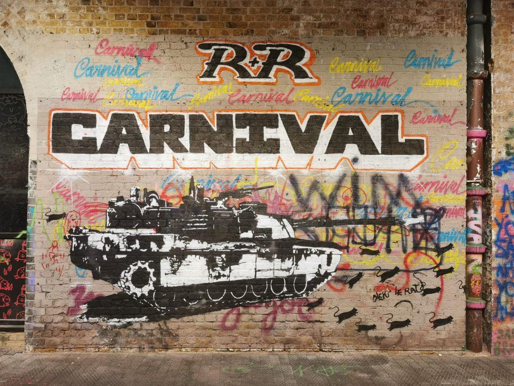 Graffiti im Leake Street Tunnel in London: Schwarzer Panzer mit dem Schriftzug „Carnival“ und einer Rattengruppe – von Blek le Rat.