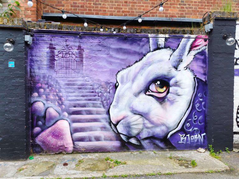 Streetart-Graffiti eines weißen Kaninchens mit großem Auge und violettem Hintergrund, London
