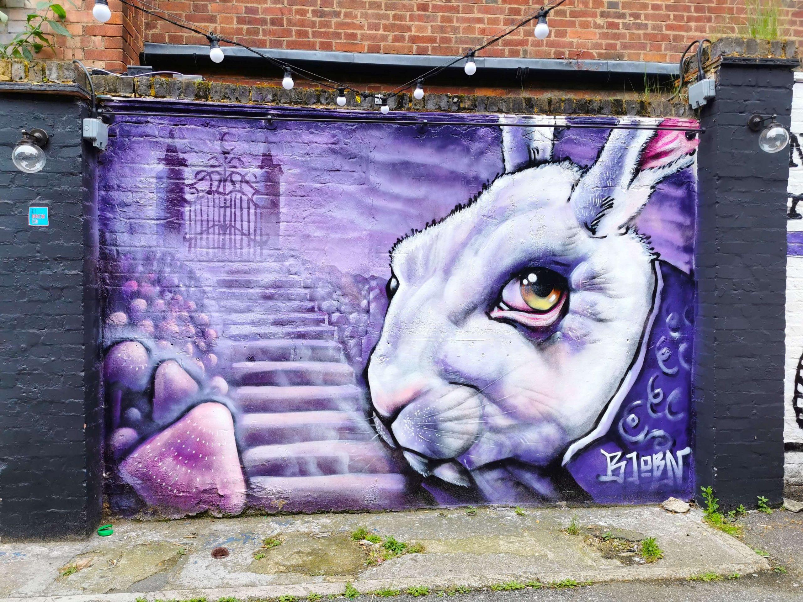 Streetart-Graffiti eines weißen Kaninchens mit großem Auge und violettem Hintergrund, London