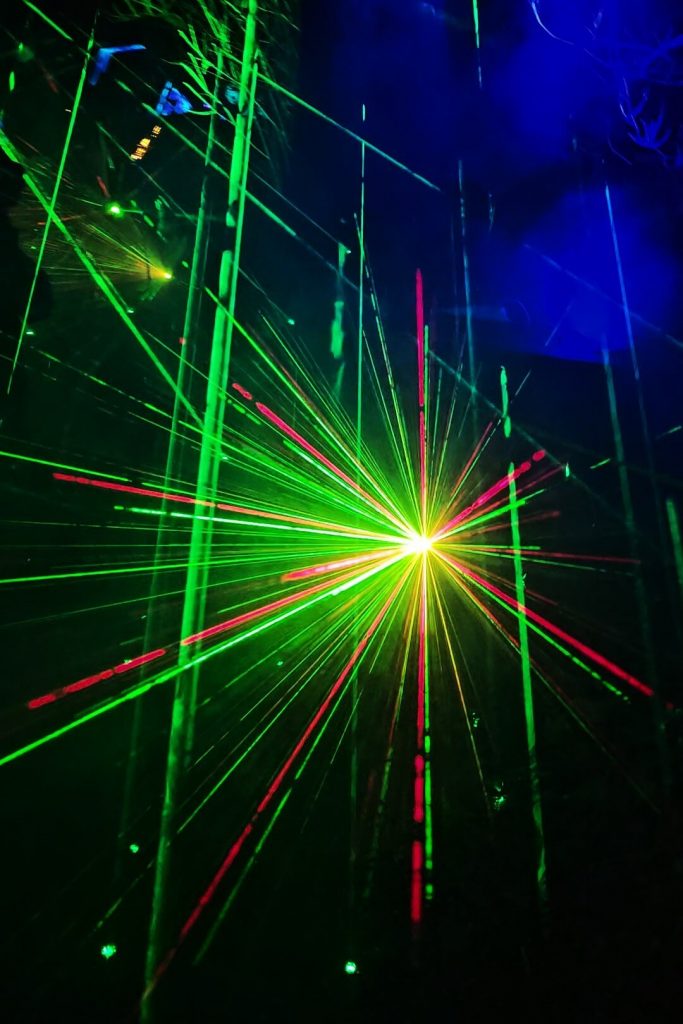 Bunte Laserstrahlen in Grün und Rot im Waldabschnitt