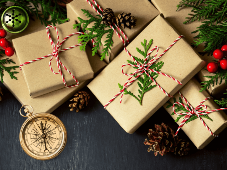 Natürlich verpackte Weihnachtsgeschenke mit Kiefernzweigen, rot-weißem Band und einem Kompass als Reise-Motiv.