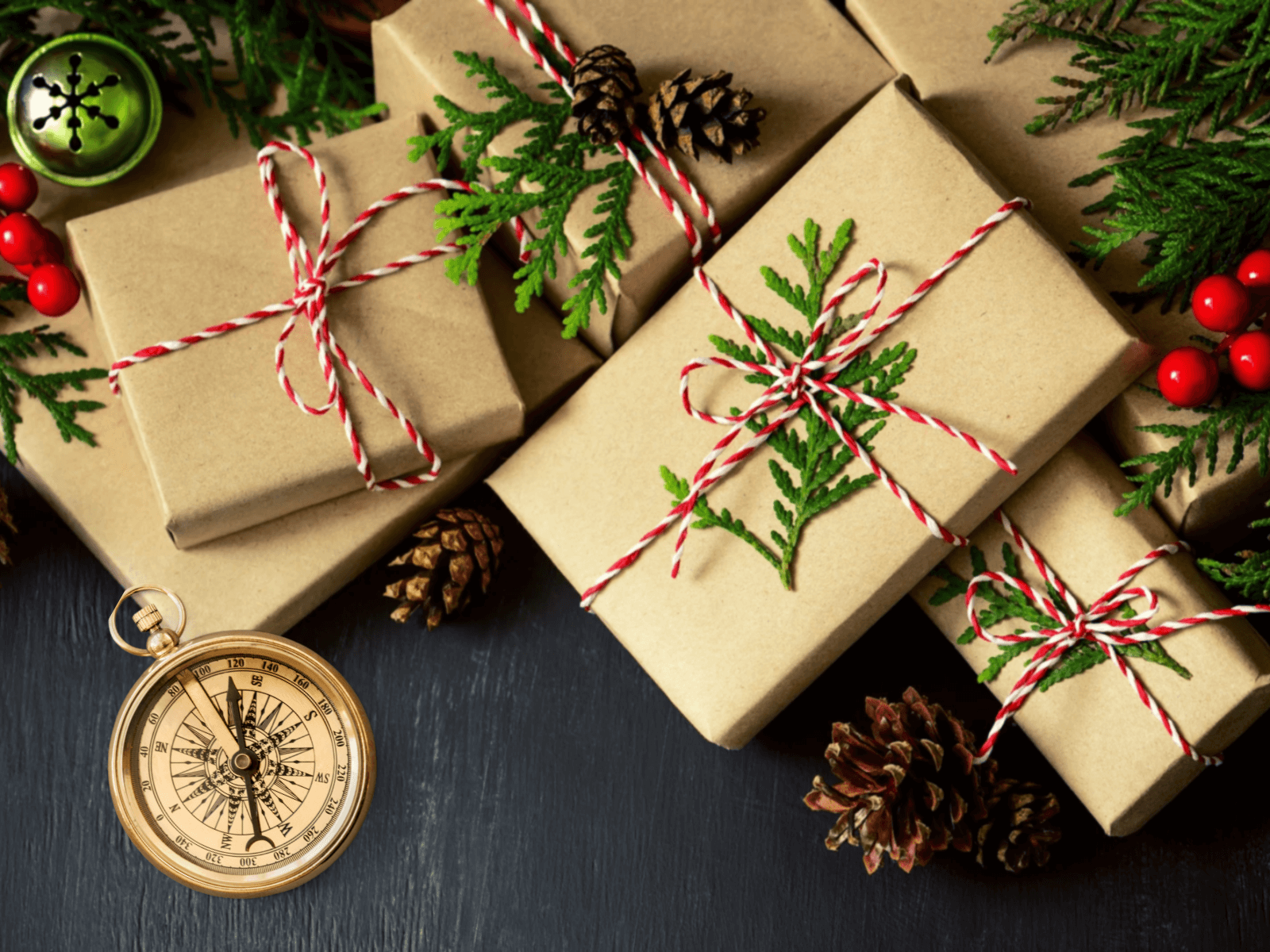 Natürlich verpackte Weihnachtsgeschenke mit Kiefernzweigen, rot-weißem Band und einem Kompass als Reise-Motiv.
