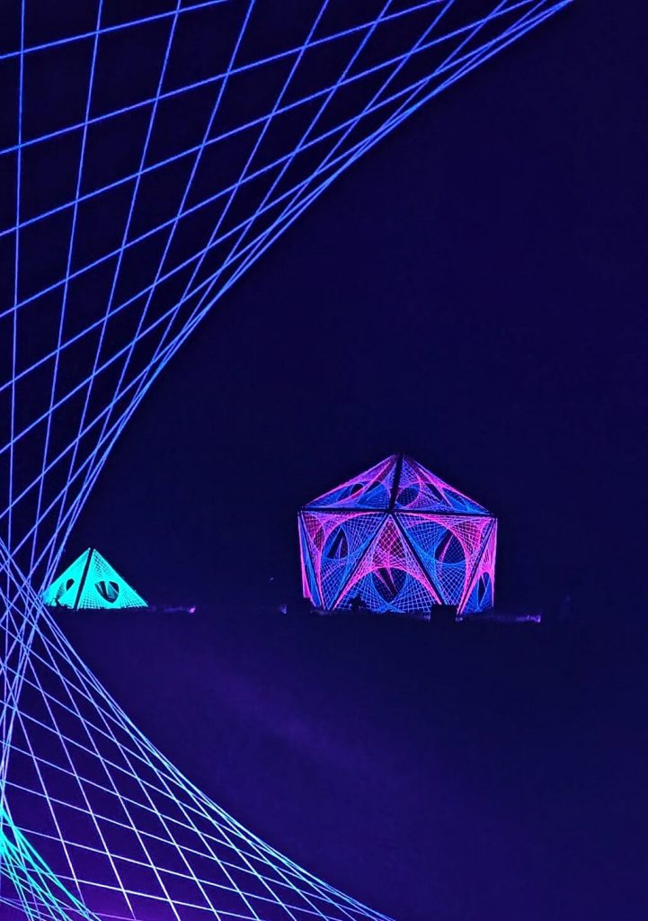 Leuchtende Netz-Skulpturen in Pink, Blau und Türkis in Haus- und Pyramidenform im Christmas Garden auf der Insel Mainau.