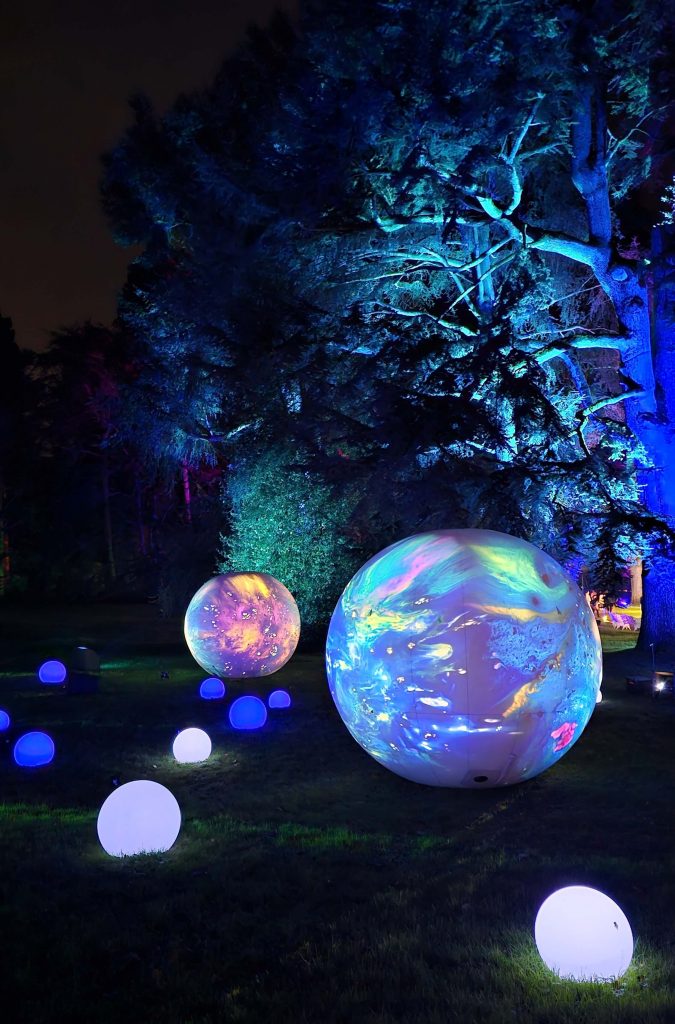 Bunte leuchtende Planeten im Wald des Christmas Garden Mainau