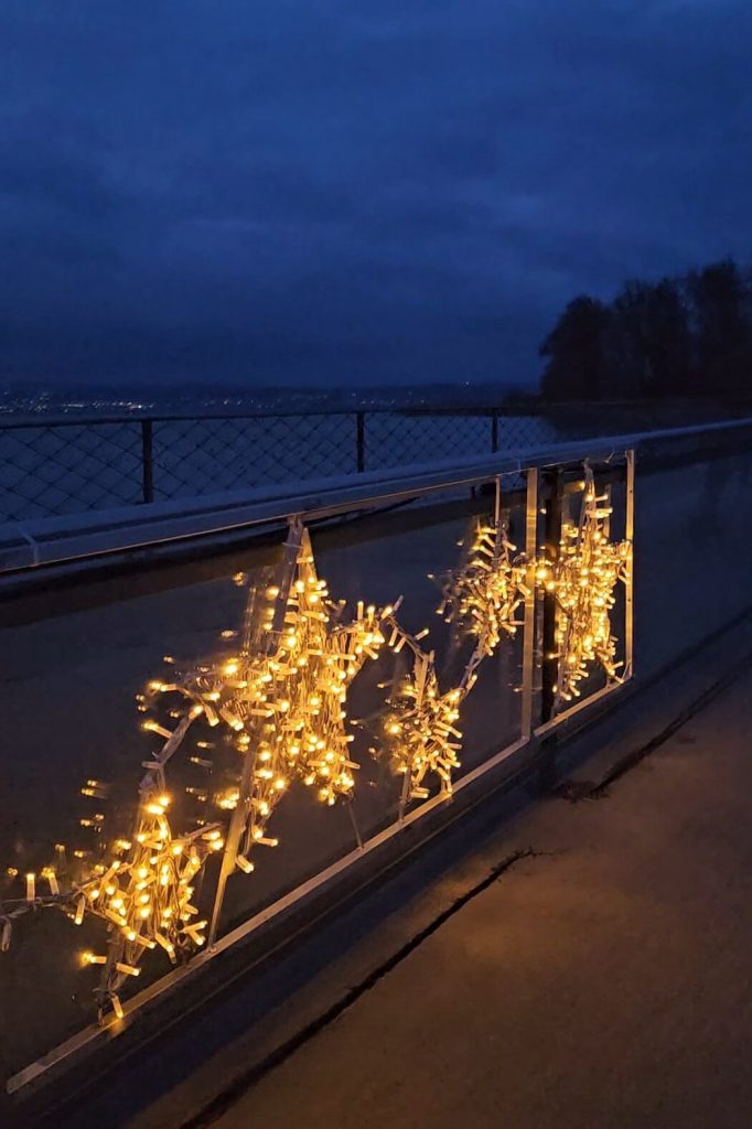 Goldene Stern-Lichterkette an einem Geländer über dem Bodensee