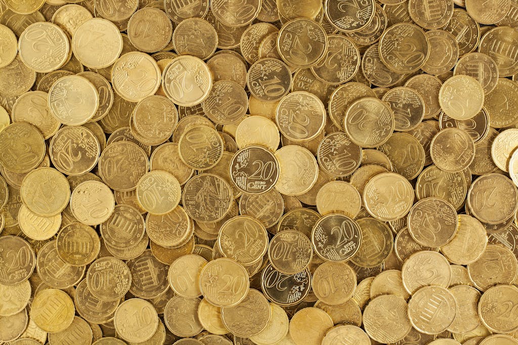 A close-up shot of Euro coins scattered in a pile, showcasing a rich golden texture.