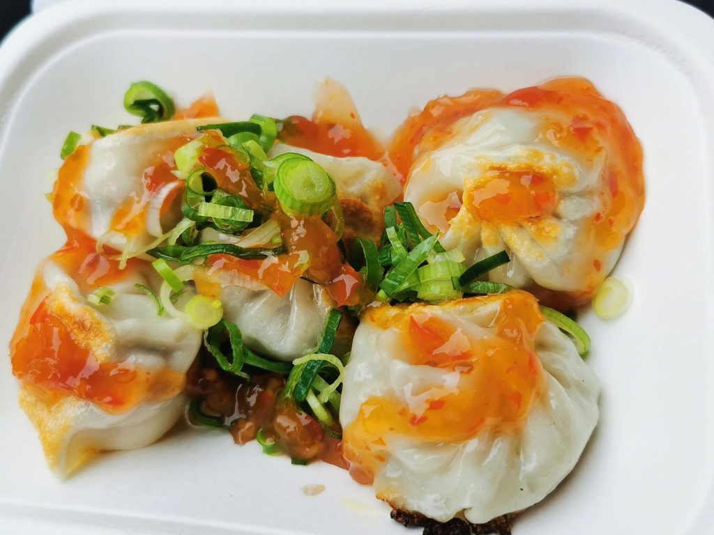 Frisch zubereitete Dumplings mit Frühlingszwiebeln und Sauce vom Streetfood-Markt in Brick Lane London