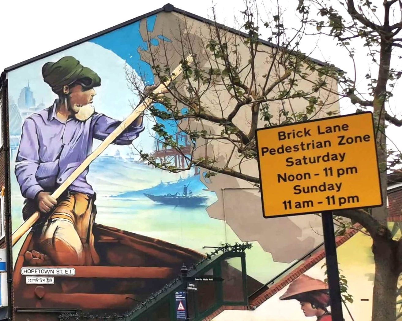 Eingang zur Brick Lane in London mit großer Streetart an einer Hauswand