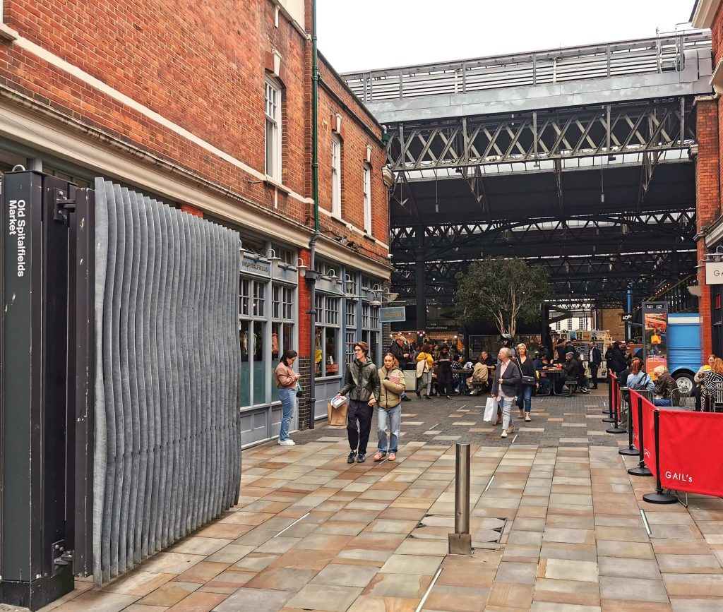 Eingang zum Old Spitalfields Market in London mit Backsteingebäuden und Besuchern im Marktbereich