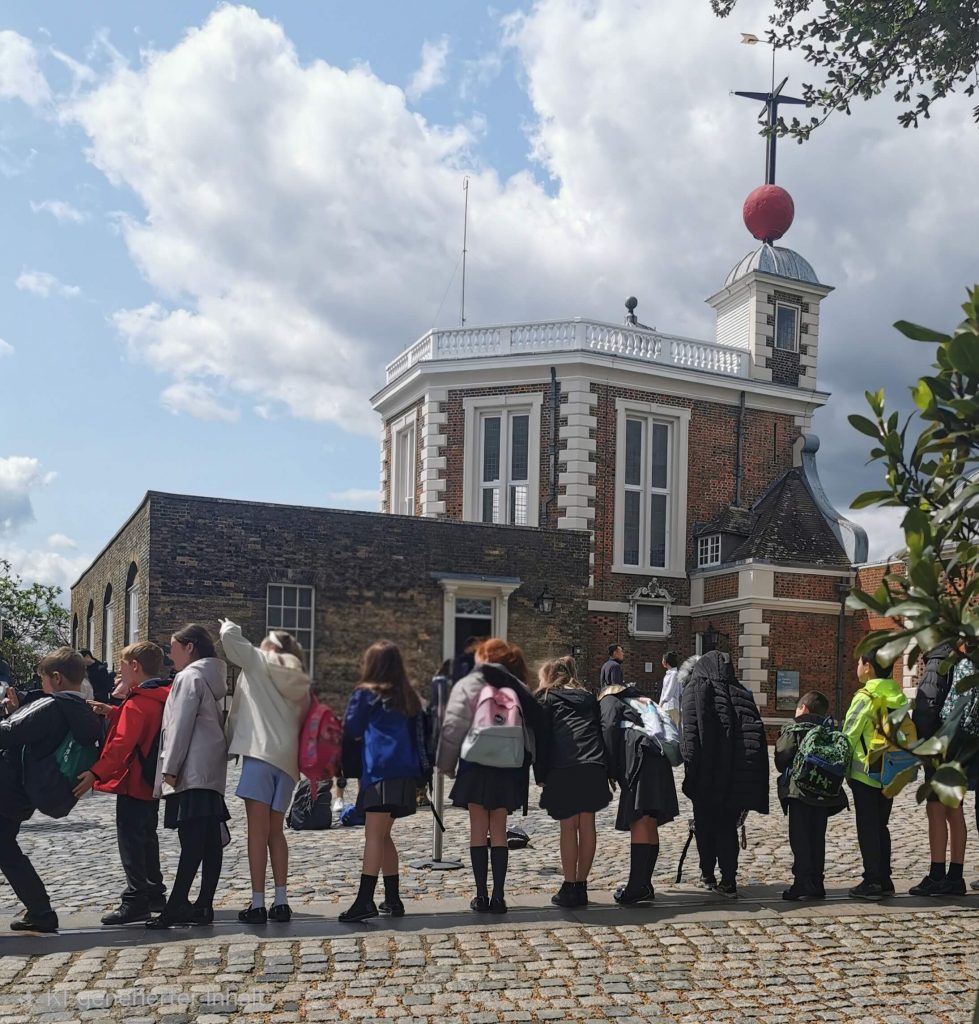 Menschen stehen am Nullmeridian vor dem Royal Observatory in Greenwich London