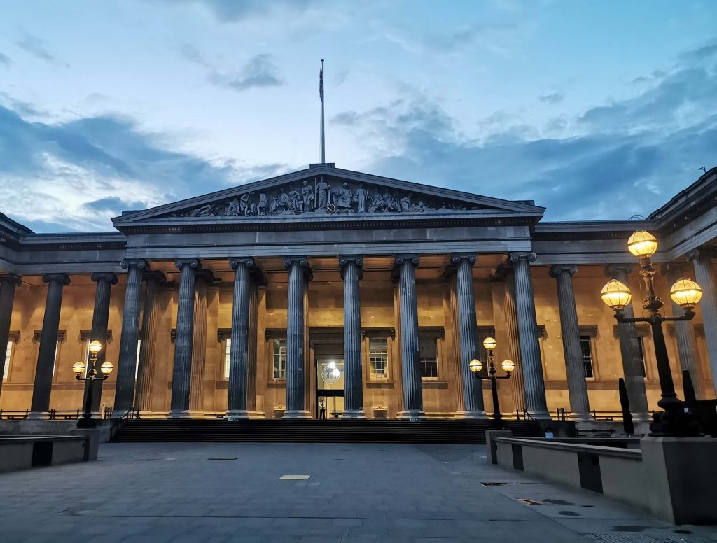 Beleuchtete Außenfassade des British Museum in London mit Säulen bei Abenddämmerung