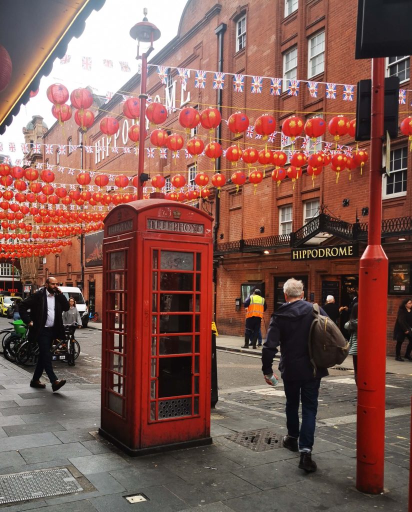 Rote Telefonzelle in Londons Chinatown mit chinesischen Laternen und Londoner Straßenszene