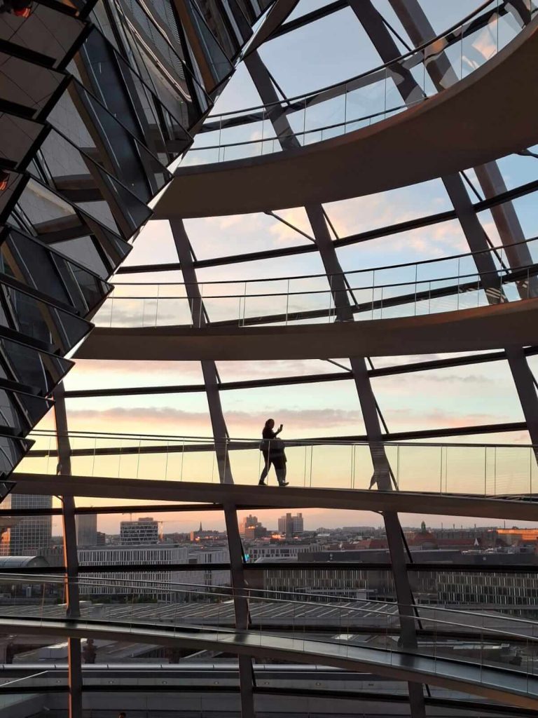 Solo-Reisende in der Reichstagskuppel bei Sonnenuntergang über Berlin