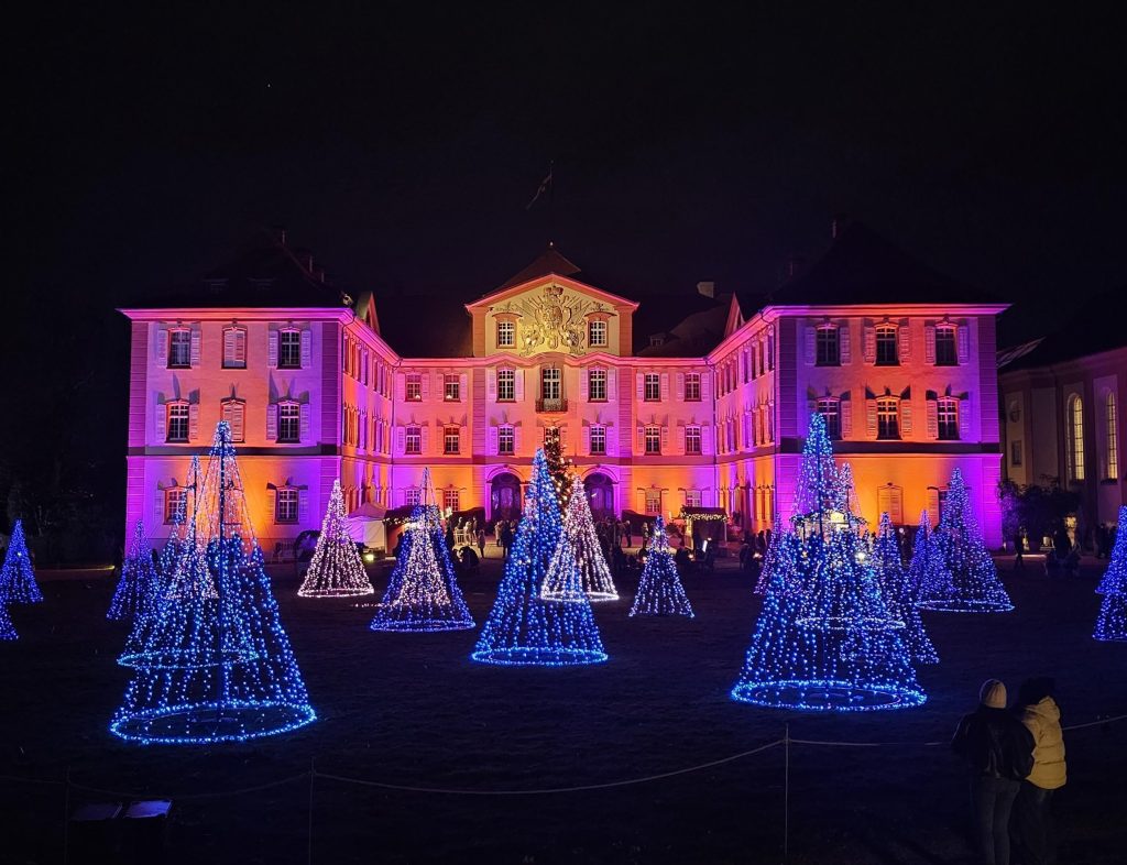 Beleuchtetes Schloss Mainau mit blauen Lichtbäumen beim Christmas Garden